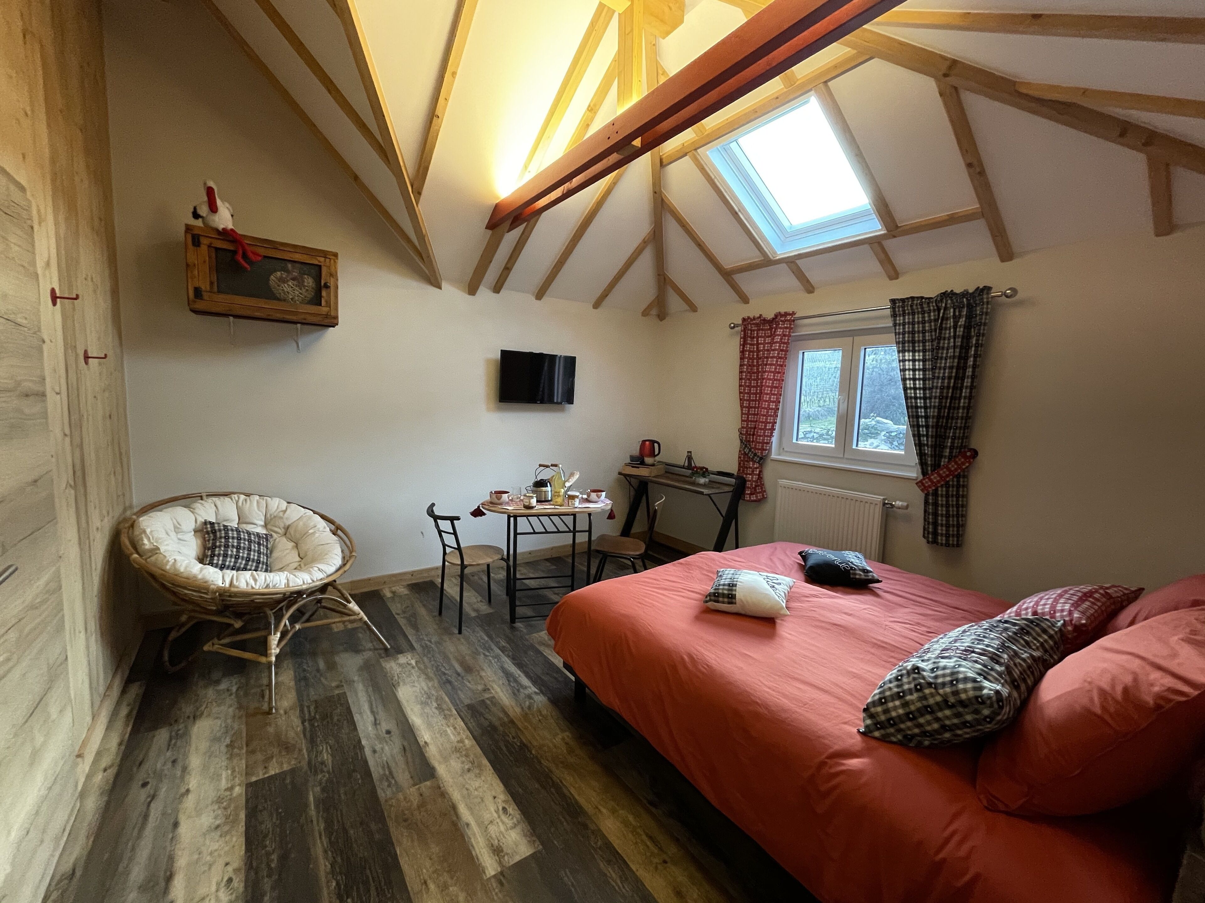 Ein gemütliches Zimmer mit Bett, Sessel, Tisch und Fernseher.