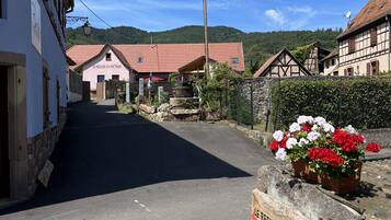 Calle con edificios tradicionales, un cartel que dice "LE REFUGE DU PART" y una maceta de piedra.