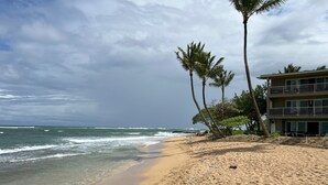 A beach with a building that has multiple balconies overlooking the ocean. - Beach Front, Pool, Amazing Sunrise! Welcome to Oceanside Retreat At Kapaa, Kauai (Kapaʻa)