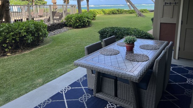 A patio with a table and chairs, a small potted plant, and a view of the ocean. - Beach Front, Pool, Amazing Sunrise! Welcome to Oceanside Retreat At Kapaa, Kauai (Kapaʻa)