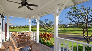 A covered outdoor seating area with wooden furniture and a view of a golf course. - Honu Hale at Kukui'ula: Elegant Poipu Home w/ Pool, Spa & AC (Koloa)
