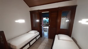 Una habitación pequeña con dos camas individuales, techo de madera y suelo de baldosas.