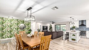 Una cocina moderna con comedor, muebles de madera y un ventanal grande.