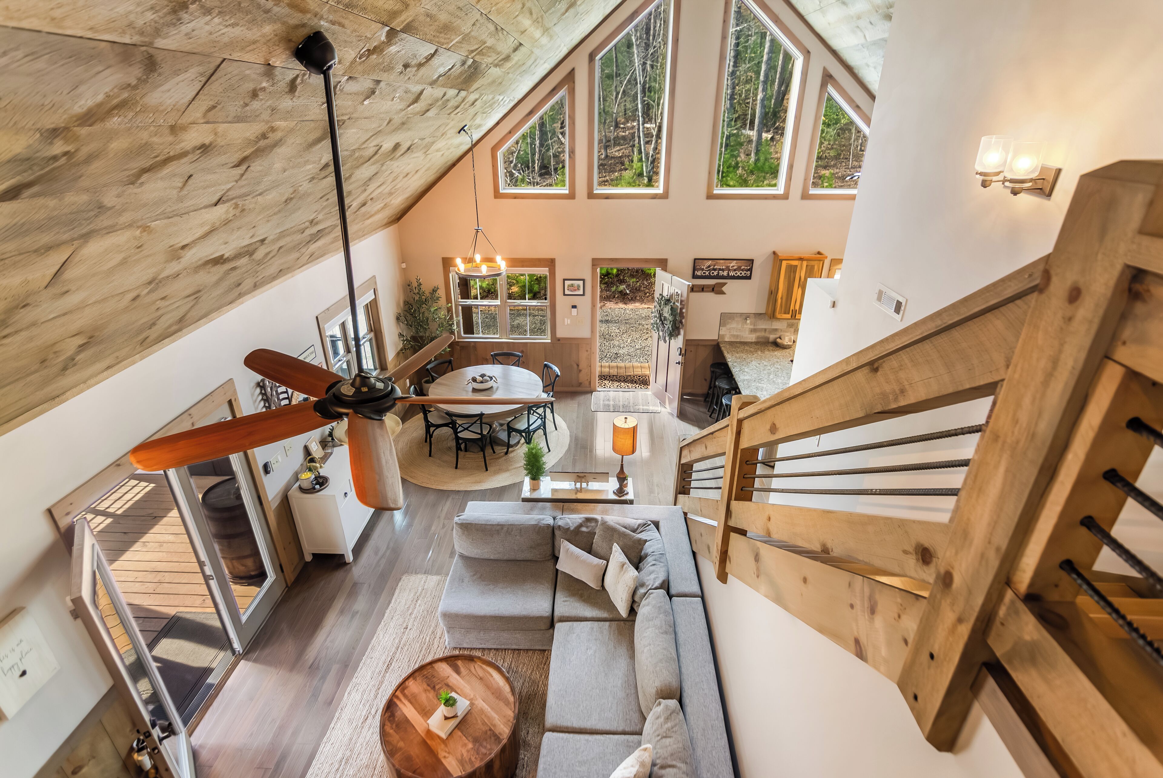 Um amplo loft com uma grande escada de madeira, espaço de jantar e área de estar aconchegante com ventilador de teto.