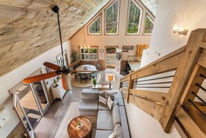 Spazioso loft con una grande scalinata in legno, zona pranzo e un angolo salotto accogliente con ventilatore a soffitto.
