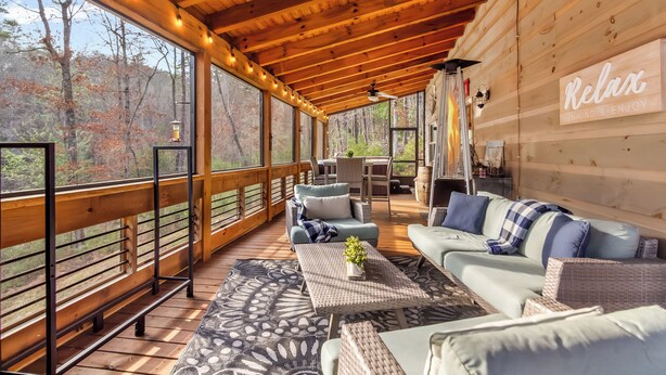 A wooden deck with a sofa, a table, and a sign that says 'Relax.' - Cozy Blue Ridge Escape •Hot Tub•Fireplace-2 acres with covered porch/Fireplace (Mineral Bluff)