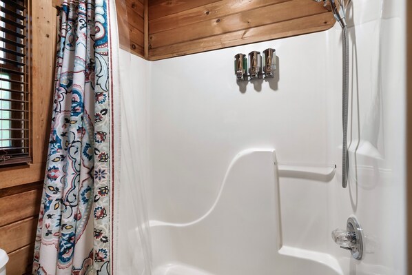 A bathroom with a white bathtub, a showerhead, and a faucet.