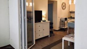 A compact living space with a sliding glass door leading to a balcony, a kitchenette with a microwave and sink, and a dining area with a table set for two. - House facing the sea (Passoscuro)