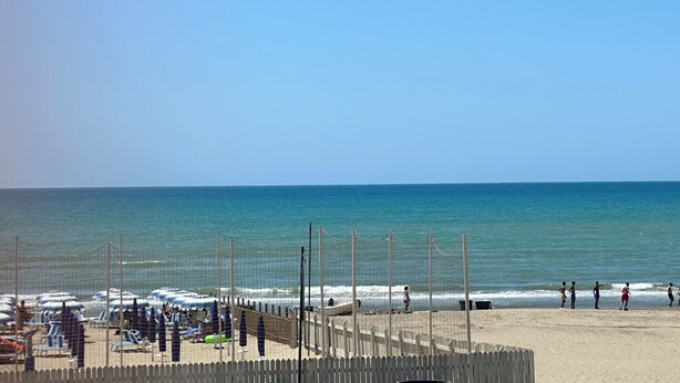 A beach with a wooden fence, umbrellas, and lounge chairs. - House facing the sea (Passoscuro)
