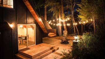 A modern house with a glass door entrance, wooden deck, and string lights.