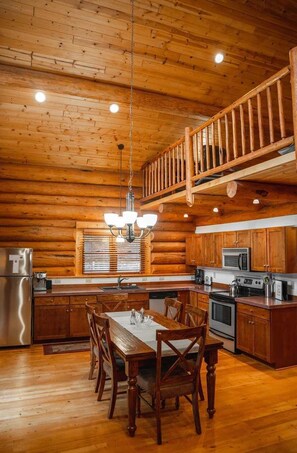 L’intérieur d’une cabane en rondins comprend un coin repas, une cuisine et un escalier en bois.