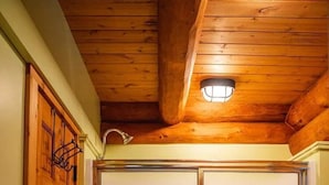 Habitació amb sostre de fusta, una porta corredissa amb panells de vidre motllat i una lluminària sobre la porta.
