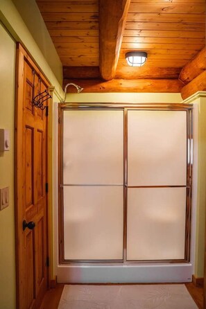Ein Zimmer mit Holzboden, einer Schiebetür mit satinierten Glasscheiben und einer Leuchte darüber.