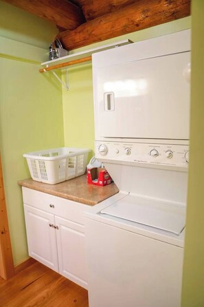 Une cuisine de taille réduite avec un réfrigérateur blanc, un lave-linge et un plafond en bois.