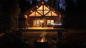 Eine Blockhütte mit Feuerstelle und Sitzbereich im Freien.