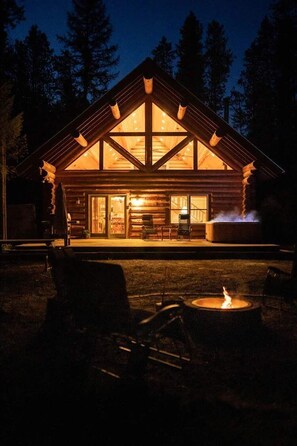 Une cabane en rondins dotée d’un grand porche à l’avant, d’un foyer et d’une cheminée bien visible.