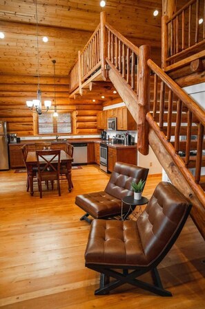 L’intérieur d’une cabane en rondins comprend un coin repas, une cuisine et un escalier en bois.