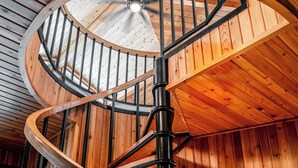Eine Wendeltreppe aus Holz mit Deckenventilator, ein Holztisch mit Lampe und eine Holzwand.