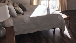 Ein Schlafzimmer mit einem Bett, einem Nachttisch mit Lampe und einem Fenster mit Vorhängen.