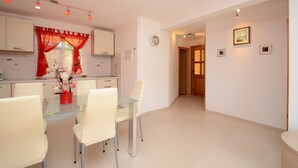 A modern kitchen with white cabinets, a glass dining table, and red curtains. - Apartments Korčula - Two Bedroom Apartment with Terrace and Sea View (Prižba)