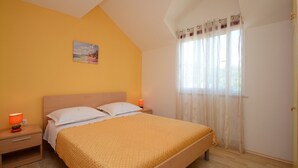 A bedroom with a bed, a nightstand, a lamp, and a window with curtains. - Apartments Korčula - Two Bedroom Apartment with Terrace and Sea View (Prižba)