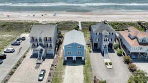 Une propriété située en bord de mer, comprenant plusieurs maisons, avec une plage en arrière-plan et un ciel dégagé.
