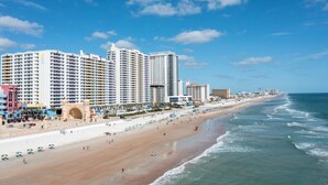 A beachfront hotel with multiple high-rise buildings, a sandy beach, and ocean waves.