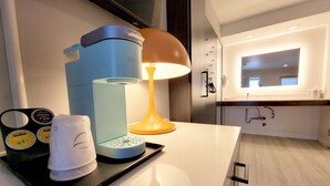A modern hotel room with a coffee maker, a lamp, and a tray with a towel and coffee cups. - Signature Inn Santa Clara (Santa Clara)