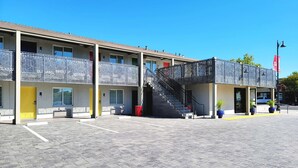 A two-story motel with a covered outdoor area, a staircase, and a flag. - Signature Inn Santa Clara (Santa Clara)