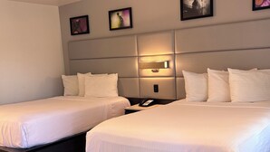 A hotel room with two single beds, a bedside table with a phone, and a wall-mounted light fixture. - Signature Inn Santa Clara (Santa Clara)