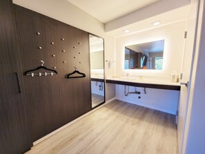 A modern bathroom with a dark wooden wardrobe, a white sink, and a large mirror.