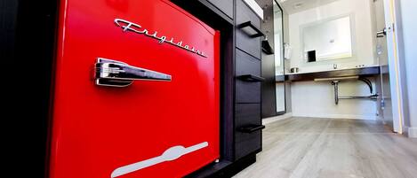 A red vintage-style safe with the word "Frigidaire" on it, located in a modern kitchen with a wooden floor and a white countertop.