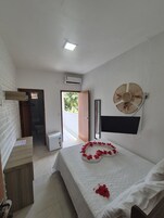 Un dormitorio con cama, ventilador de pared, aire acondicionado y vistas al exterior.