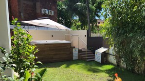 A backyard with a covered patio, a brick wall, and a palm tree. - Pousada Beach Garden (Ipojuca)