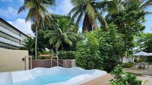 A swimming pool with a wooden deck, surrounded by lush greenery and palm trees. - Pousada Beach Garden (Ipojuca)