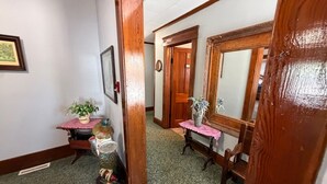 A hallway with a wooden door, a mirror, a small table with a vase, and a bench. - Historic Home | Walk to Lake & Strip Fun (Geneva)
