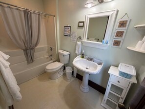 A bathroom with a bathtub, toilet, sink, and a mirror.