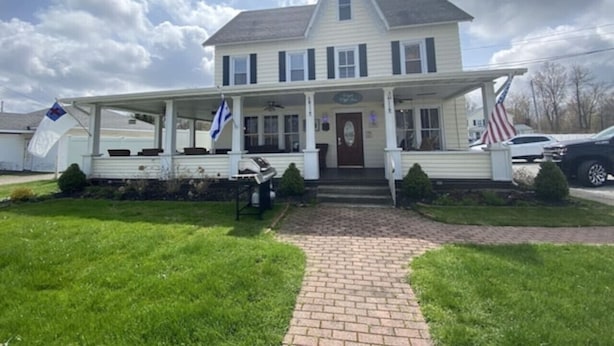 A two-story house with a porch, a front door, and two flags. - Historic Home | Walk to Lake & Strip Fun (Geneva)