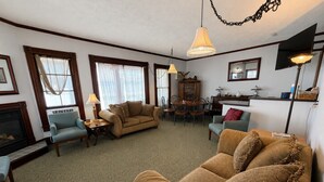 A living room with a fireplace, two sofas, a dining table with chairs, and a chandelier. - Historic Home | Walk to Lake & Strip Fun (Geneva)