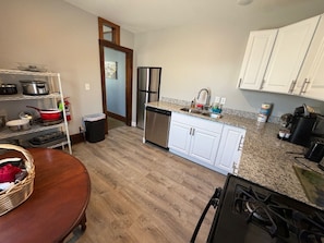 A kitchen with white cabinets, a stainless steel refrigerator, a dishwasher, and a granite countertop.