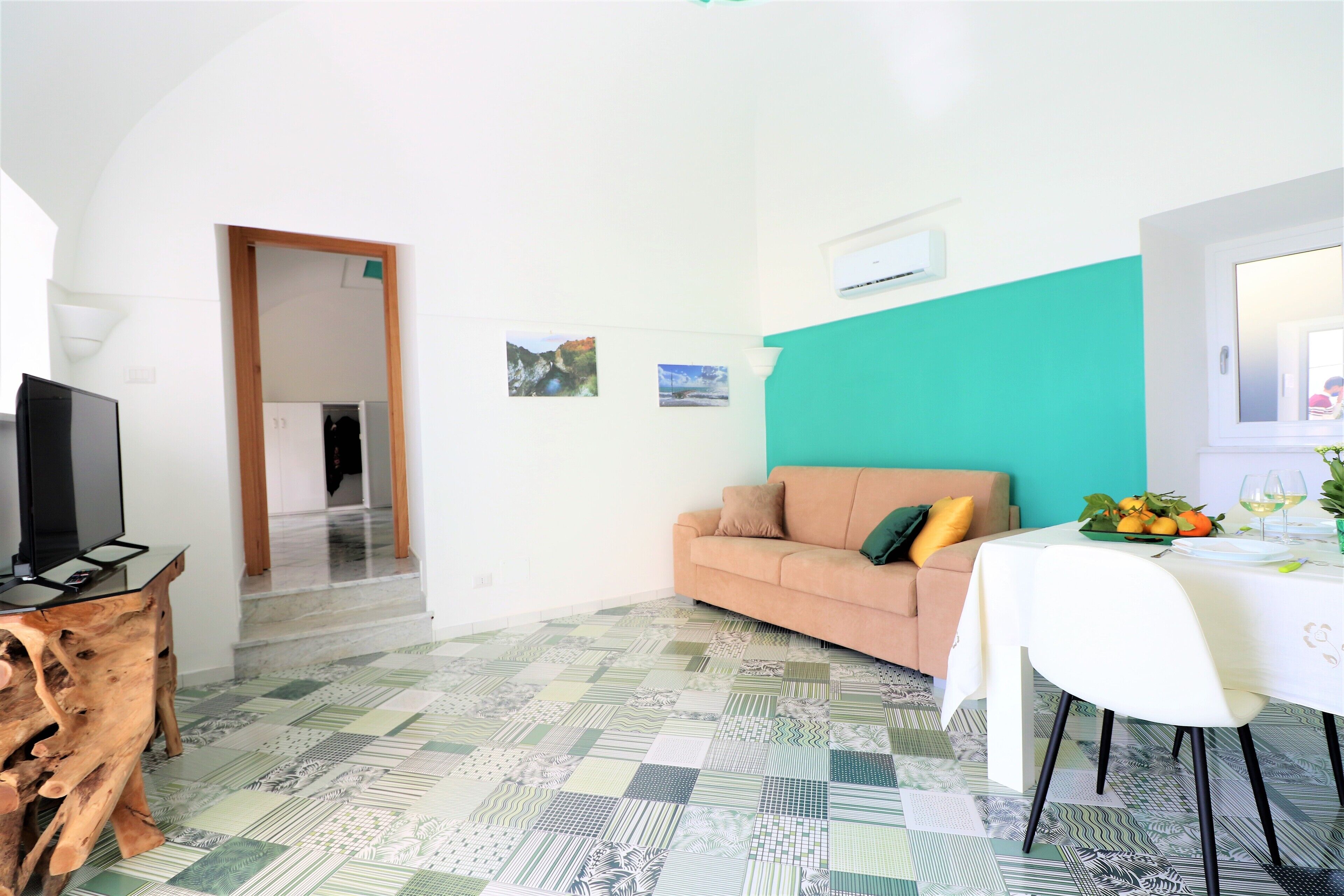 A living room with a sofa, a coffee table, a TV, and a patterned floor.