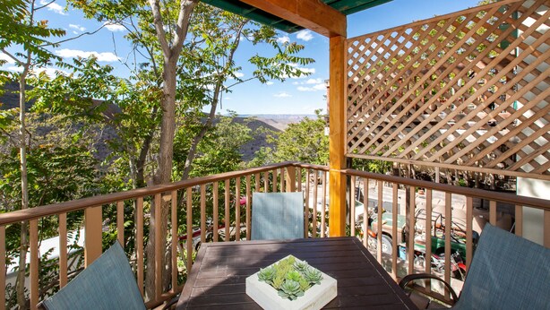 A wooden deck with a table and chairs, overlooking a mountainous landscape.