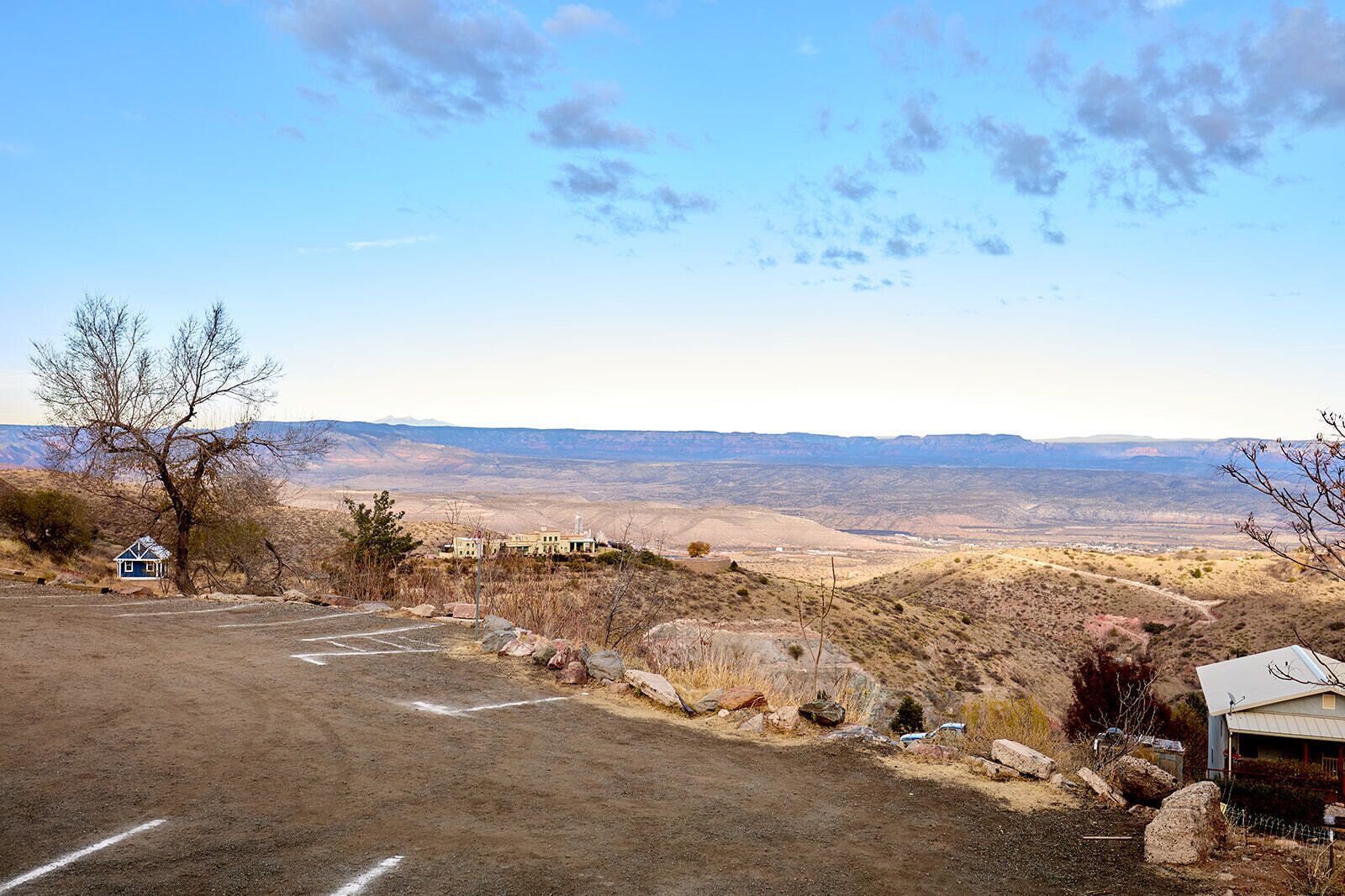 Une route menant à un bâtiment doté d’un parking et offrant une vue sur une vallée.