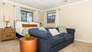 A bedroom with a bed, a blue sofa, a round copper side table, and a nightstand.