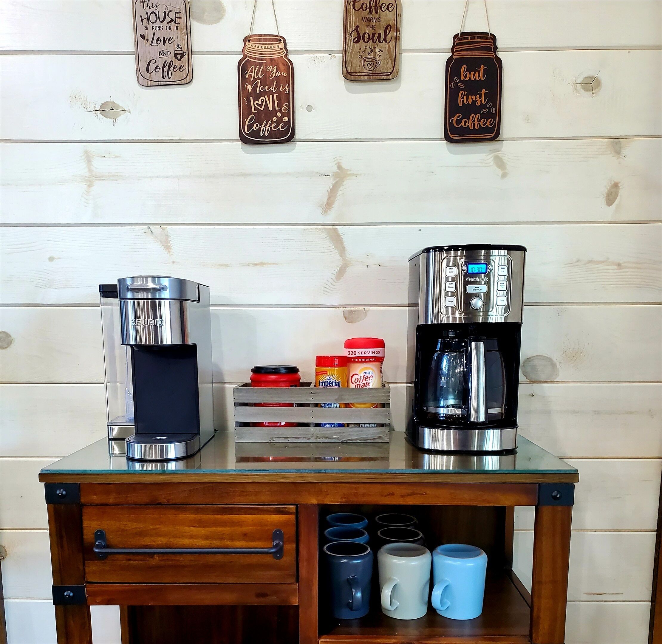 Een koffiehoek met twee koffiezetapparaten, een koffiemolen en een presentatie van koffiemokken.