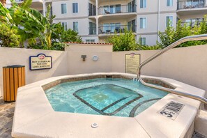 A hot tub with a sign indicating hot tub hours and a spa rules sign.