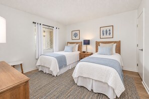 A double room with two beds, a bedside table, a lamp, and a window with curtains.