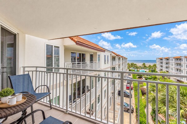 Un balcon donnant sur une plage et d’autres bâtiments.