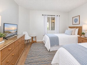 A bedroom with a bed, bedside tables, a TV, a desk, and a chair.