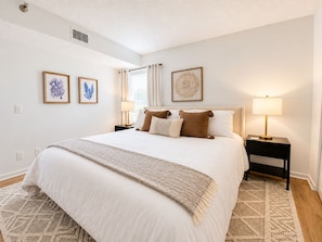A neatly arranged bedroom with a large bed, two bedside tables, and wall art.